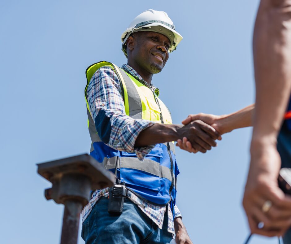 A friendly Huskies Homefix contractor in a hard hat and hi-vis vest shaking hands with a happy customer